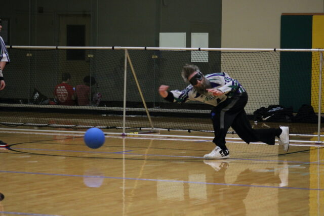 Goalball player throwing the ball during an indoor game.