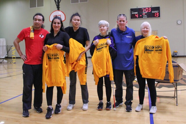 Group of people posing for photo holding yellow sweatshirts.