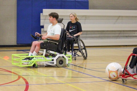 Several young people playing power soccer on an indoor court.