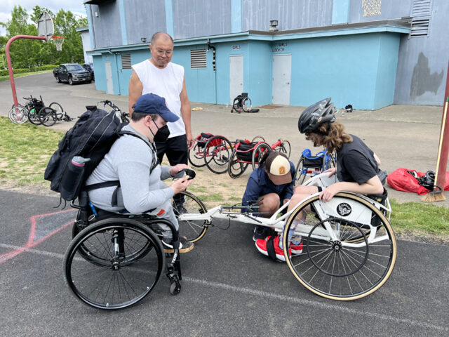 Athletes examining bicycles on a track.