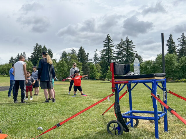 Athlete throwing javelin in background of track and field event.