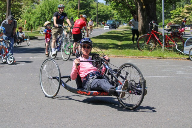 Woman handcycler in a road race with others on various types of cycles.