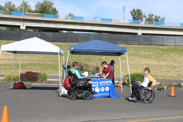 Adaptive Sports Northwest tent and table at an outdoor handcycling event.