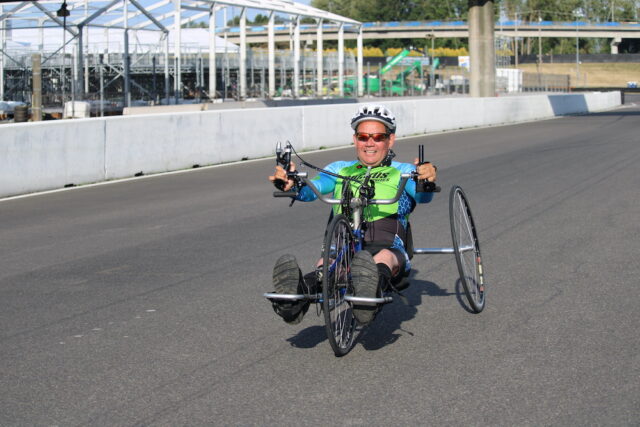Man riding a handcycle on an outdoor track.