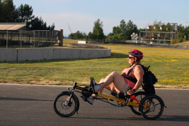 Woman riding a handcycle on an outdoor track.