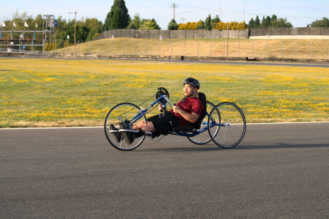 Man riding a handcycle on an outdoor track.