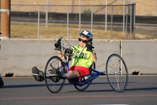 Person riding a handcycle on an outdoor track.