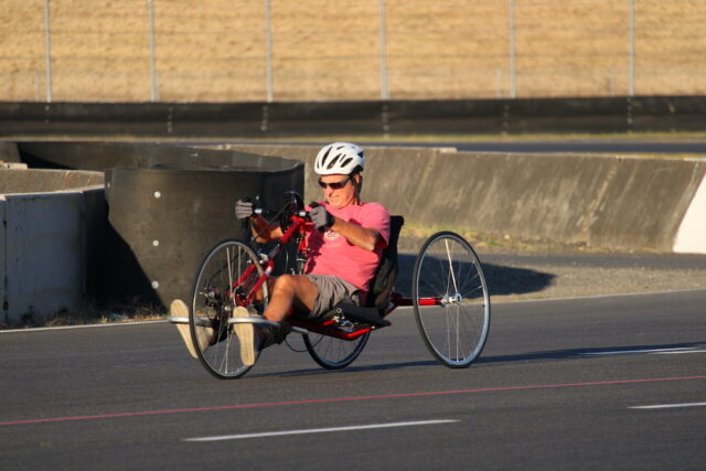 Person riding a handcycle on an outdoor track.