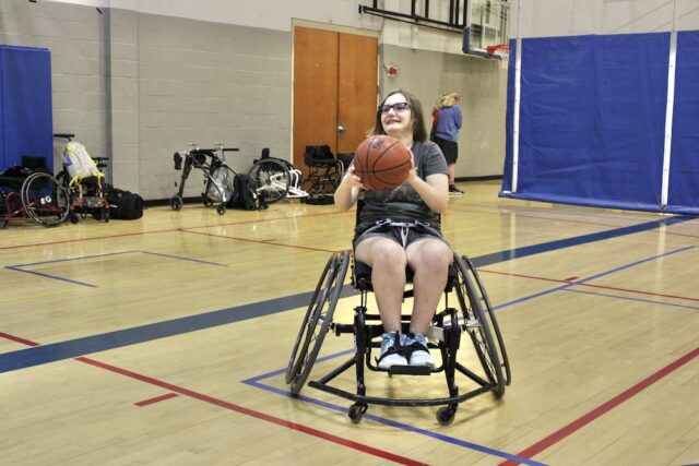 Female wheelchair basketball player with the ball.