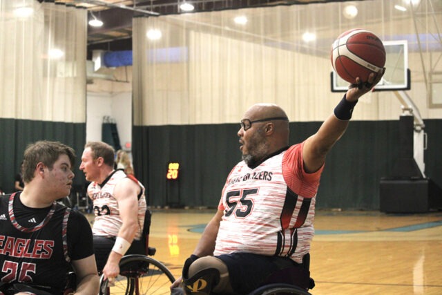 Blazers player holds a basketball in one hand near an Eagles player.