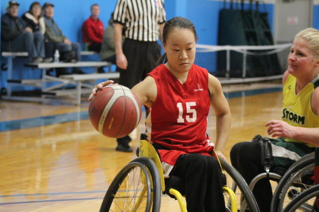 Young woman wheelchair basketball player on an indoor court.