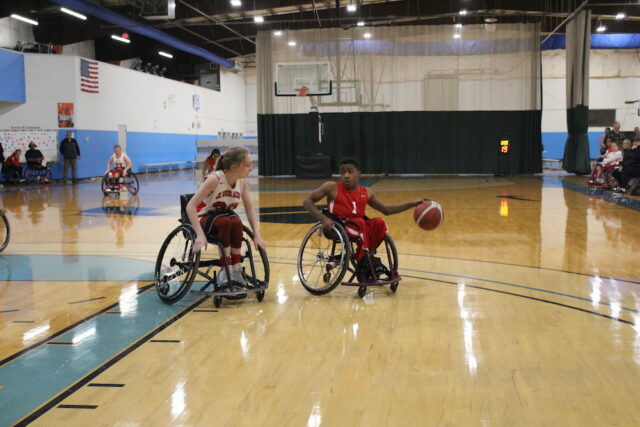 Young wheelchair basketball game on an indoor court.