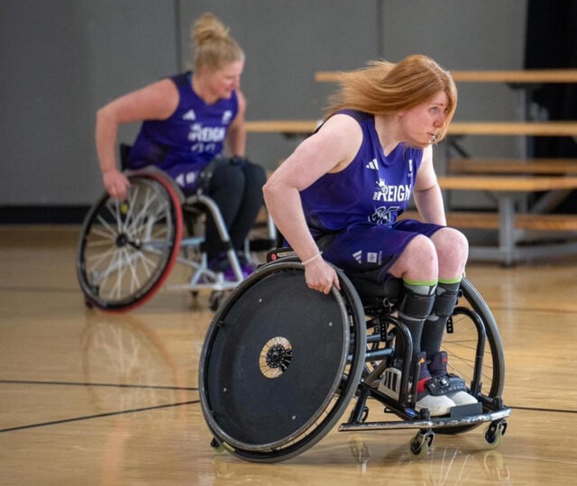 Two women on the Reign team moving quickly playing wheelchair basketball.