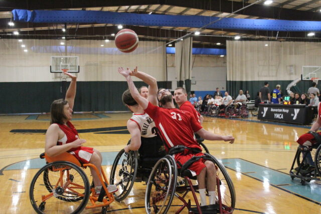 Adult wheelchair basketball game on an indoor court.