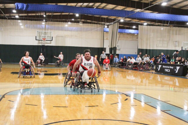 Young wheelchair basketball game on an indoor court.