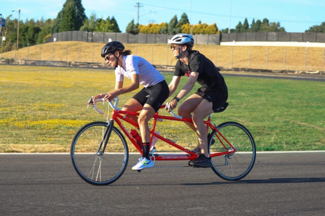 Cyclers on a two-person bicycle on an outdoor track.