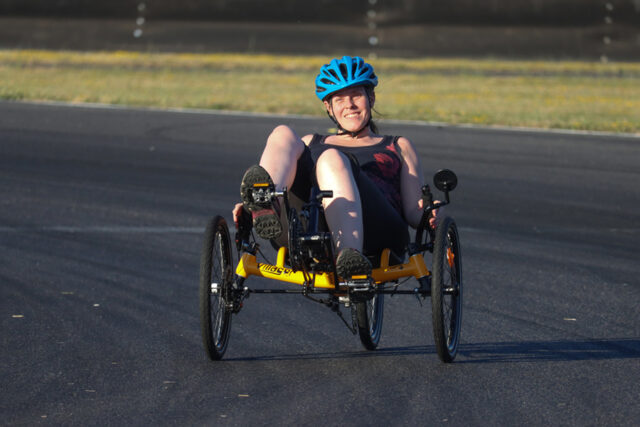 Woman riding an adaptive bike on a track on a sunny day,