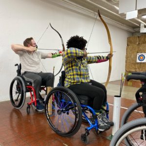 Archers with bows drawn in an indoor range.