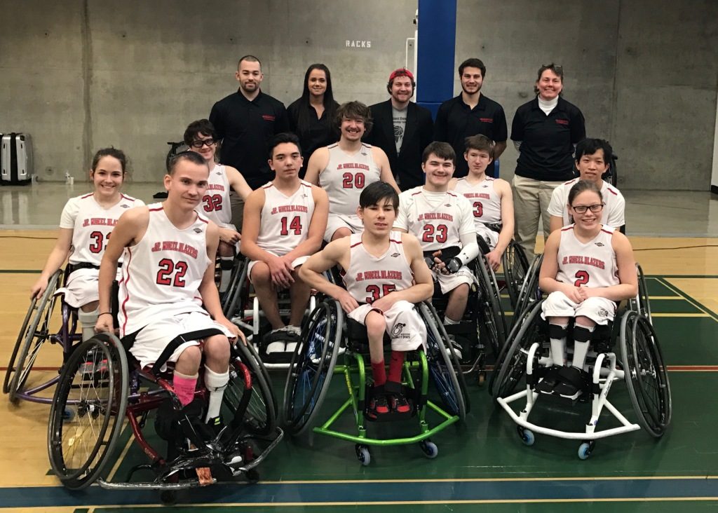 Wheelchair basketball team and coaches posing together.