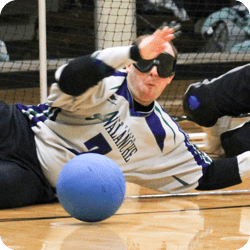 Goalball athlete blocking the net from an incoming ball.