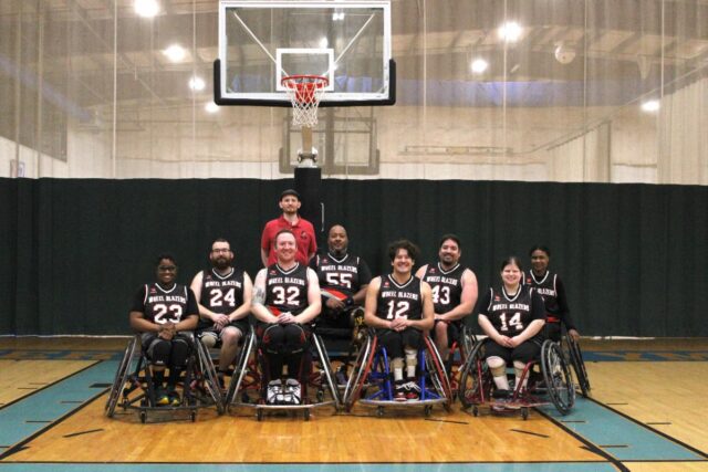 Adult wheelchair basketball team and coach posing.