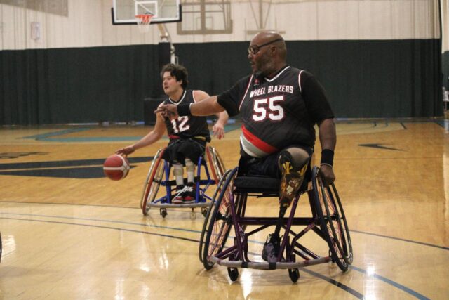 Wheelchair basketball game on in indoor court.
