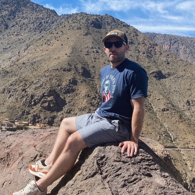 Kalin Boodman, sitting on a rock during a summer hike.