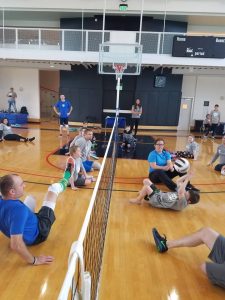 People playing seated volleyball on an indoor court.