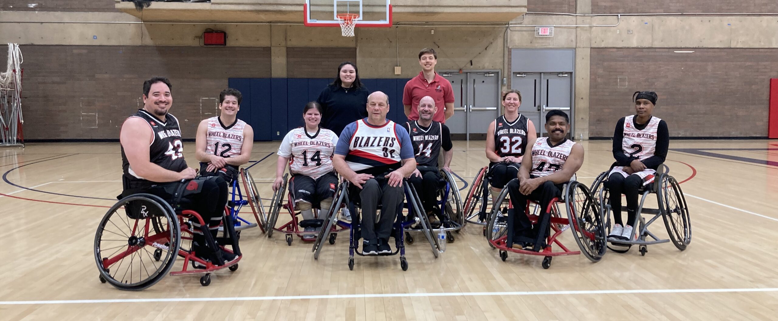 Team of wheelchair basketball players wearing uniforms and smiles.